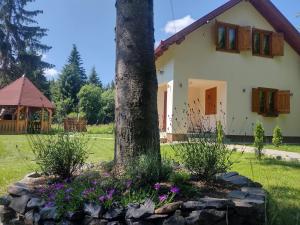 a house with a tree and flowers in the yard at Weekend-Hause in Mădăras