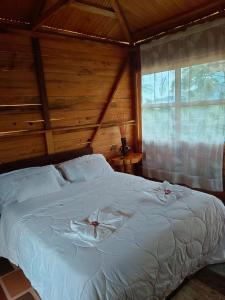 sypialnia z łóżkiem z białą pościelą i oknem w obiekcie CABAÑA LOS NOGALES w mieście San Agustín
