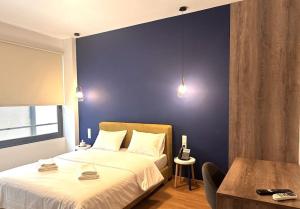 een slaapkamer met een groot bed met een blauwe muur bij Luxury Suites Athens 2 in Athene