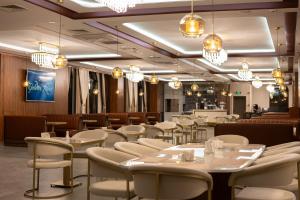 a restaurant with white tables and chairs and chandeliers at Golden River Hotel By Continent in Arnavutköy