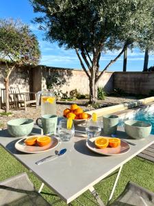 une table avec des oranges et des verres de jus dans l'établissement Appartement l'Arancetu vue mer avec piscine, à Biguglia