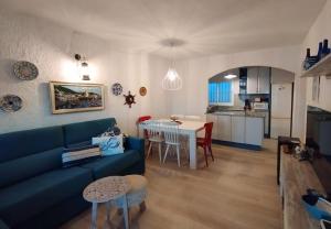 sala de estar con sofá azul y cocina en Casa Platja d'en Robert, en Port de la Selva