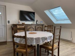 a dining room with a table with chairs and a tv at 211 - T3 entièrement rénové en plein centre de Plurien à moins de 5 minutes des Plages in Plurien