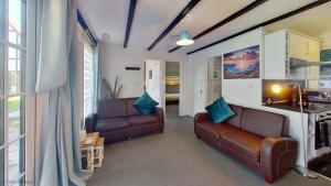 a living room with two leather couches and a kitchen at 12 Tudor Court, Tolroy Manor in Hayle