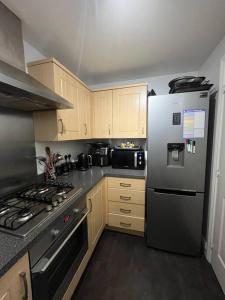 een keuken met een roestvrijstalen koelkast en houten kasten bij Aycliffe Home Away From Home A1 in Newton Aycliffe