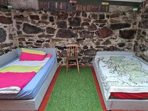 duas camas num quarto com uma parede de pedra em Squealing Pig Bothy em Bragor