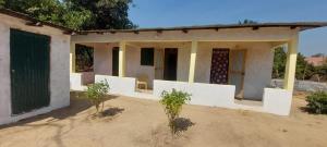 a house with white walls and trees in front of it at Petit Hollande guest rooms in Abémé