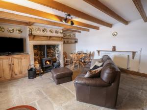 a living room with a leather couch and a fireplace at Swinhope View in Hexham