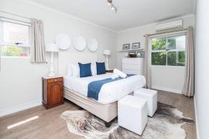 a white bedroom with a large bed with blue pillows at Green Point Living with Stadium View in Cape Town