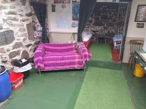 - un canapé dans une pièce dotée d'un mur en pierre dans l'établissement Squealing Pig Bothy, à Bragor