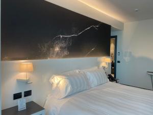 a bedroom with a white bed with a large painting on the wall at Life Hotel in Bergamo
