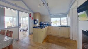 a large kitchen with wooden cabinets and a large window at G23 Norda, Riviere Towans in Hayle