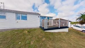 a white house with a porch and a car at G23 Norda, Riviere Towans in Hayle