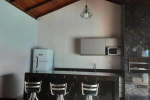 cocina con encimera con sillas y nevera en Espaço Dunei - Casa inteira com piscina en Catas Altas