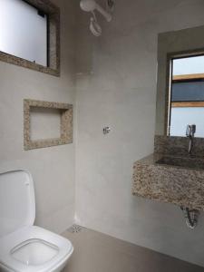 a bathroom with a white toilet and a sink at Espaço Dunei - Casa inteira com piscina in Catas Altas