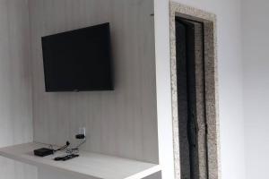 a flat screen tv on a wall with a shelf at Espaço Dunei - Casa inteira com piscina in Catas Altas