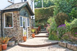 a garden with a stone house with a patio at Beautiful character cottage in Saint Mawgan