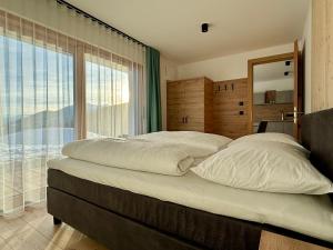 a bedroom with a large bed with a large window at Schneiderhof, Urlaub auf dem Bauernhof in Ridanna