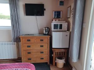 a small room with a microwave and a dresser with a microwave at Dunroaming Cabin in Pendine