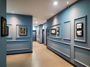a hallway with blue walls and pictures on the walls at BKK Concept Hotel in Phnom Penh