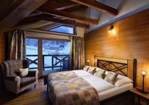 a bedroom with a bed and a chair and a window at Chalets Jasná Collection Záhradky in Belá