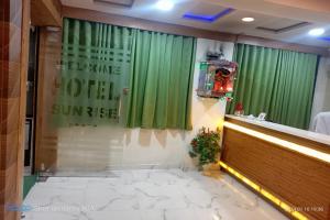 a restaurant with green curtains and a counter with flowers at Hotel Sunrise Inn in Ahmedabad