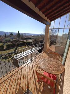 een houten terras met een tafel en stoelen op een balkon bij Maison avec piscine in Villeneuve