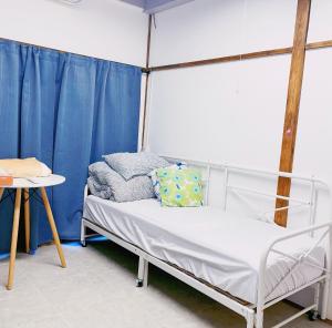 a bed in a room with blue curtains and a table at Akira&chacha杉並区世田谷direct to shinjuku for 13 min 上北沢4分 近涉谷新宿 in Tokyo