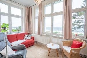 a living room with a red couch and chairs and windows at Villa Carmen in Bansin