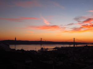 a sunset view of a bridge over a body of water at Merces by Central Hill Apartments in Lisbon