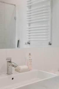 um lavatório de casa de banho com uma garrafa de sabão e um espelho em Apartament Planty 16C em Kielce