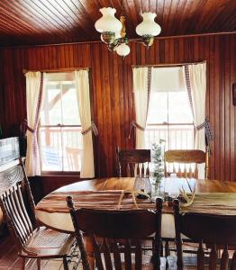 uma sala de jantar com uma mesa de madeira e 2 janelas em Camp Garcon 