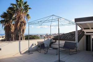 een patio met 2 stoelen op een dak met een palmboom bij La Pietra Nera - Etna Home in Catania