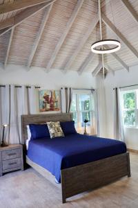 um quarto com uma cama grande e um edredão azul em The Moxy em English Harbour