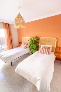 two beds in a room with orange walls at Las Flores Apartments in Nerja