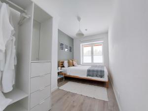 a white bedroom with a bed and a window at Modern and cosy apartment in Lahemaa national park in Kolga