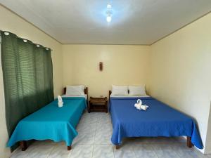 two beds in a room with blue sheets at Dancalan Beach Resort in Donsol