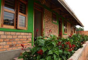 a house with red flowers in front of a building at Iziba lodge in Hoima