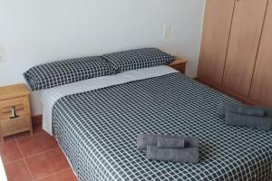 Schlafzimmer mit einem Bett mit einer schwarzen und weißen Bettdecke in der Unterkunft Acogedor apartamento en la playa de Canet in Canet d'en Berenguer