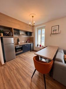 a kitchen and living room with a table and a couch at Grand gîte de la Ferme De La Tourelle in Longues-sur-Mer