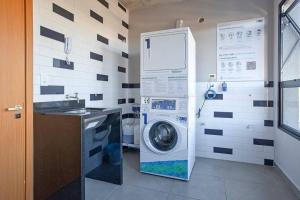 uma máquina de lavar roupa na casa de banho com um lavatório em Loft 102 em Curitiba