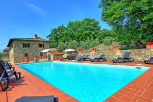 a swimming pool with chairs and a stone wall at Villa Quercina in Pieve a Presciano