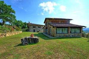 a stone house with a yard with a tree stump at Villa Quercina in Pieve a Presciano