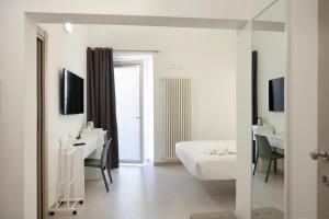 a white bedroom with a bed and a desk and a mirror at Ruffini Rooms in Termoli