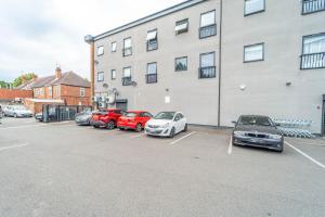 eine Gruppe von Autos, die auf einem Parkplatz neben einem Gebäude geparkt sind in der Unterkunft ChicCityApartment - Free parking - Perfect for contractors - Close to Molineux Stadium in Wolverhampton