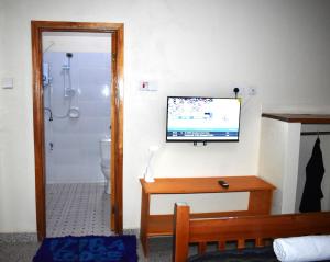 a bathroom with a television on a wall at Iziba lodge in Hoima
