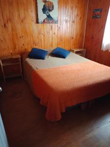 a bedroom with a bed with two blue pillows at Cabaña Totoralillo in Coquimbo