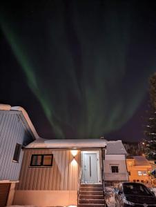 una casa con las luces del norte en el cielo en Northern living 1 room with shared bathroom en Tromsø