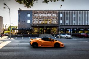 un coche naranja conduciendo por una calle frente a un edificio en HOTEL EUROPA en Komárno