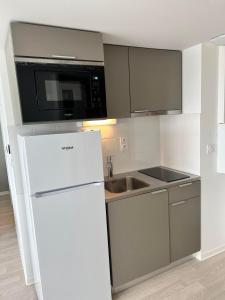 a kitchen with a white refrigerator and a microwave at HOTEL LES PORTES DE PARIS in Ivry-sur-Seine